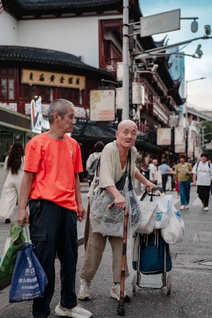 pexels photo 34073814 34073814 1 A senior man with a walker and a caregiver walking in a bustling Asian city street.